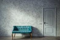 Elegant minimalist interior with a teal sofa and a white door against a grey wall.