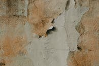 Detailed shot of a peeling, weathered wall texture showcasing rough surfaces and natural colors.